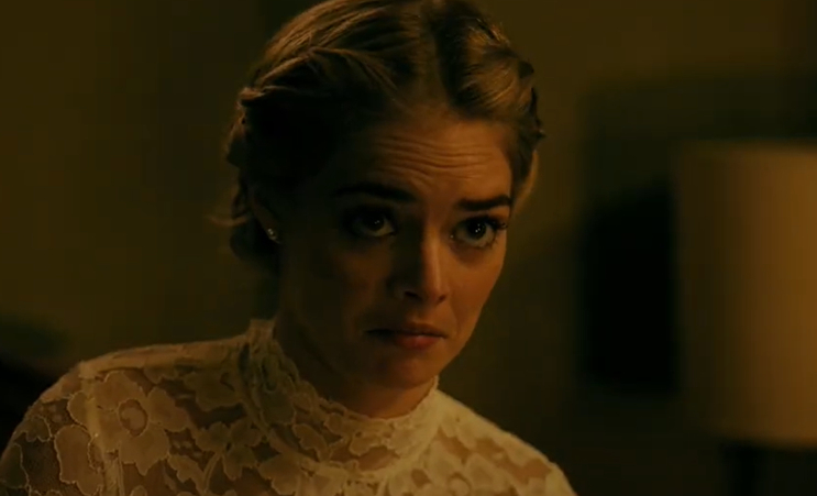 Samara Weaving with light hair styled in a braid looks intensely forward while wearing a high-neck lace dress
