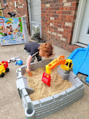 Child playing with a artifact operation acceptable successful a sandbox outside, with a artifact container successful the inheritance and scattered toys around