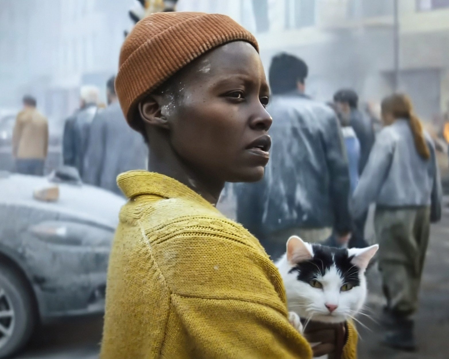 Lupita Nyong'o and Frodo standing by a crowd of people in a scene from "A Quiet Place: Day One"