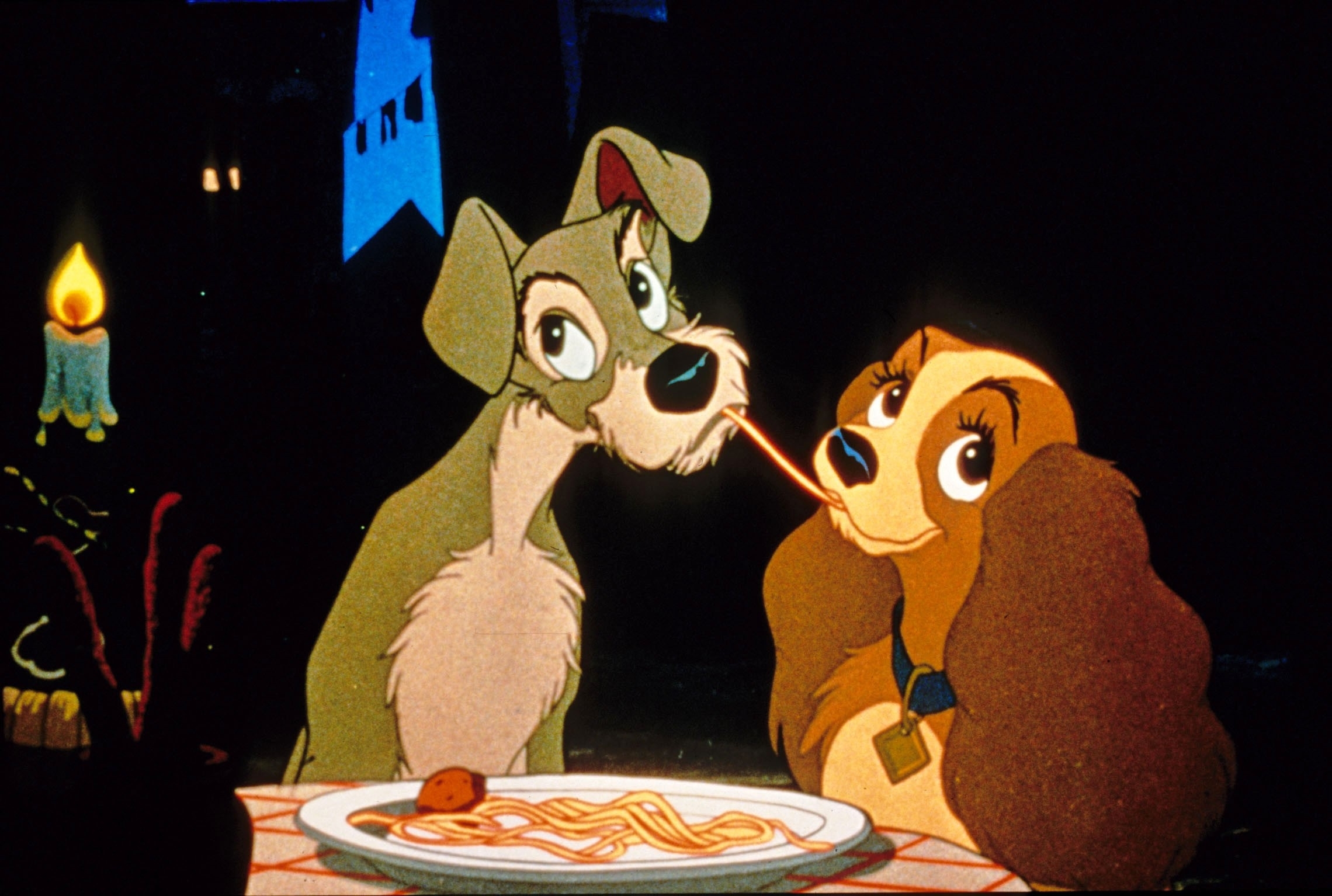 Lady and Tramp sharing a spaghetti strand at a candlelit dinner