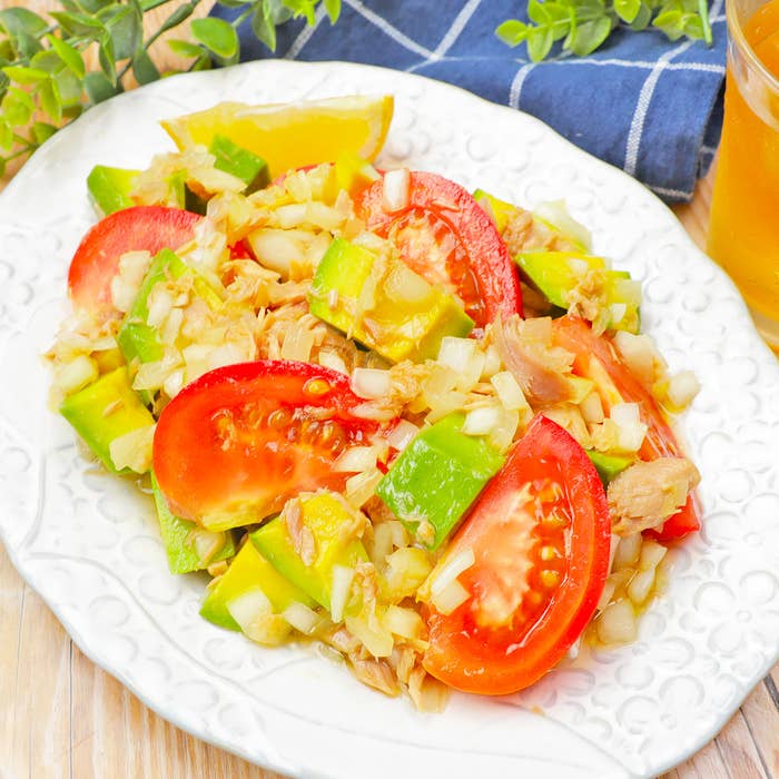 トマト、アボカド、玉ねぎ、ツナなどが盛り付けられた白い皿のサラダ。