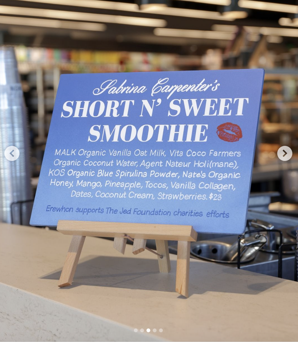 A sign promoting "Sabrina Carpenter's Short N' Sweet Smoothie" with ingredients listed and a note about Erewhon's support for the Jed Foundation charity