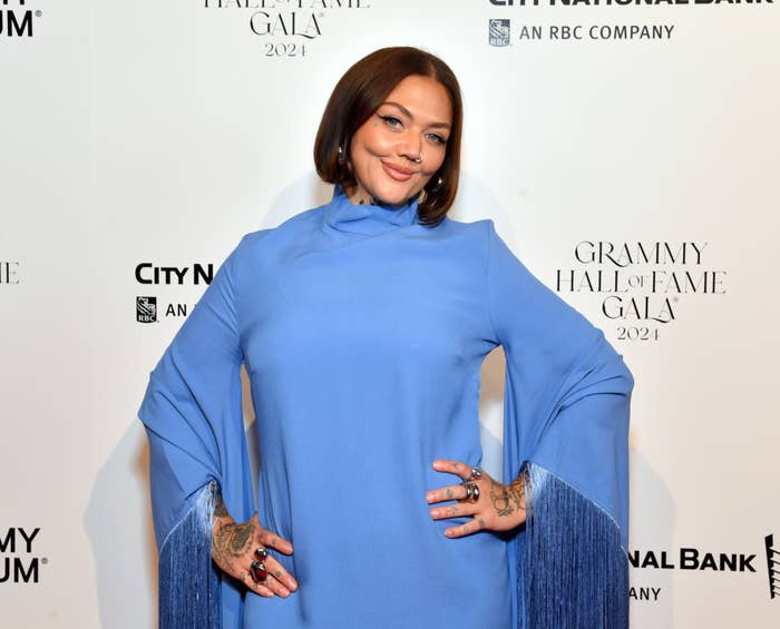 Elle in long-sleeved dress with fringe details poses with hands onher hips at Grammy Hall of Fame Gala 2021 background