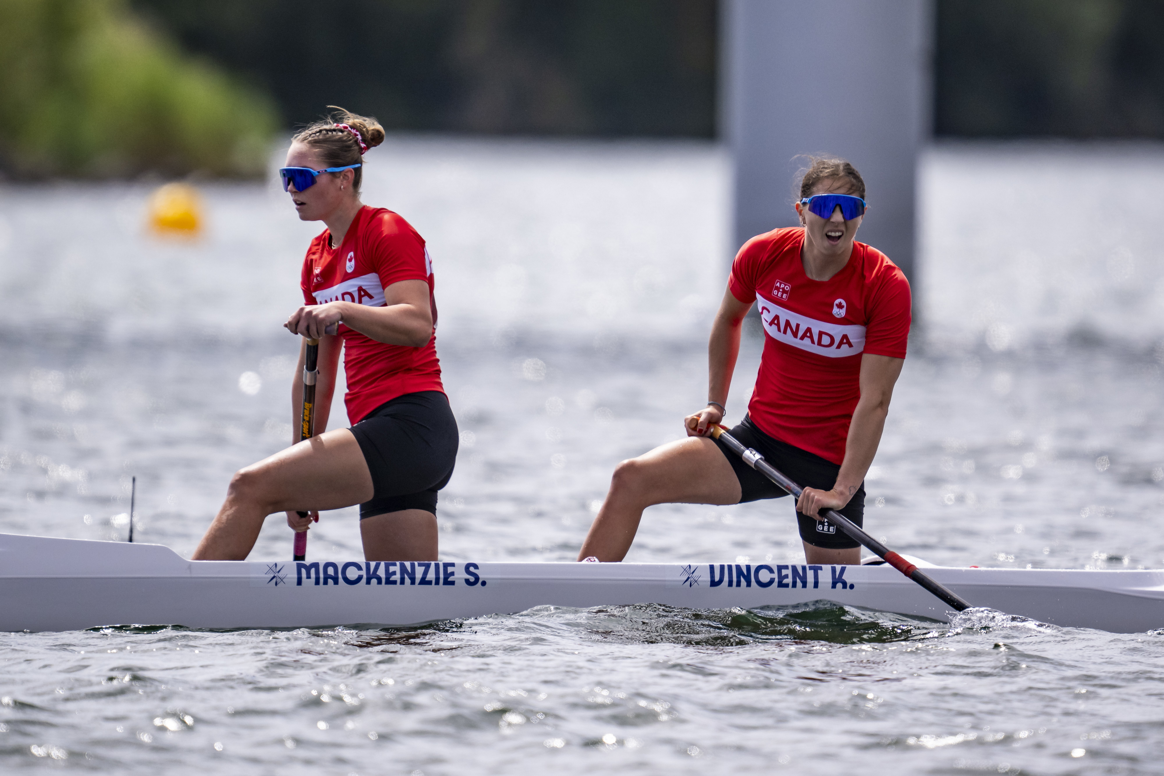 Mackenzie S. and Vincent K. are paddling a canoe during a competitive sporting event. They are wearing athletic gear with "Canada" printed on their shirts