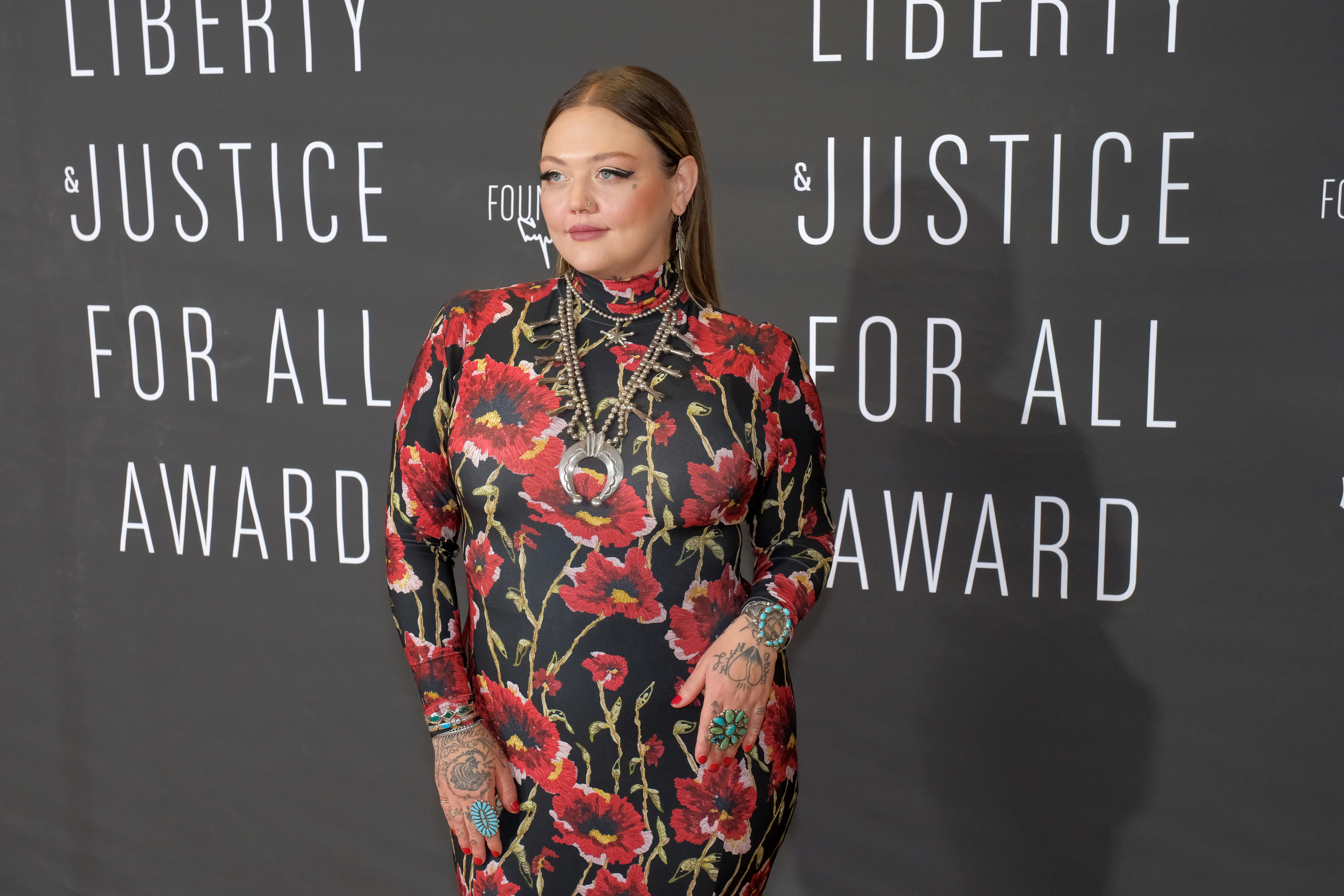 Elle King poses in a floral-patterned dress at the Liberty & Justice For All Award event backdrop
