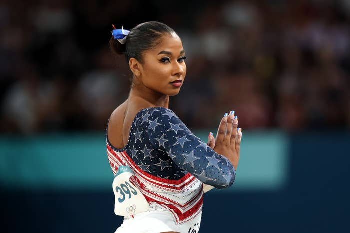 Female gymnast performing on balance beam at Olympics, wearing a star-spangled leotard