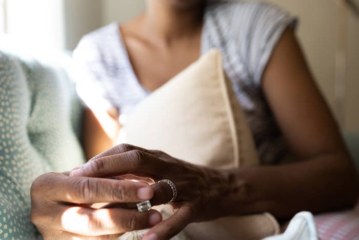 Person holding a ring with both hands, sitting on a couch and hugging a pillow
