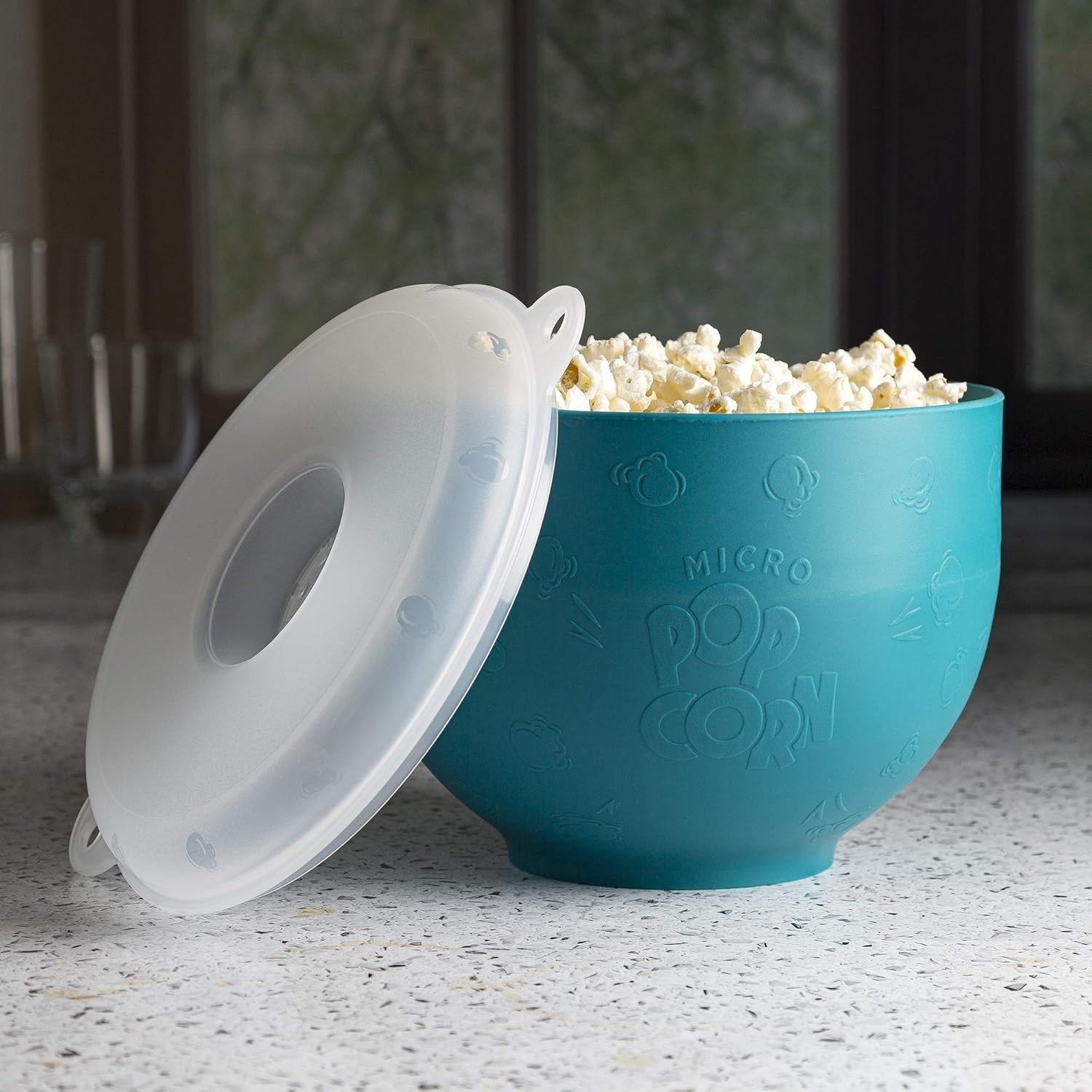 Microwave popcorn bowl with lid, filled with popcorn, set on a countertop. Bowl has &quot;Micro Popcorn&quot; text