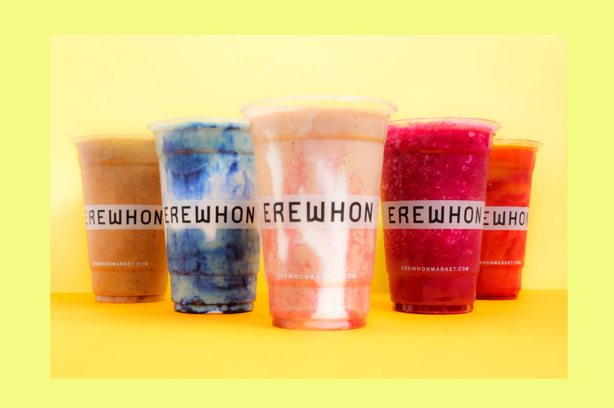 Five colorful smoothie cups from Erewhon Market with varying textures and ingredients displayed against a yellow backdrop