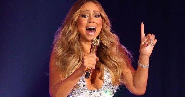 Mariah Carey passionately singing into a gold microphone, wearing a sparkling, low-cut dress