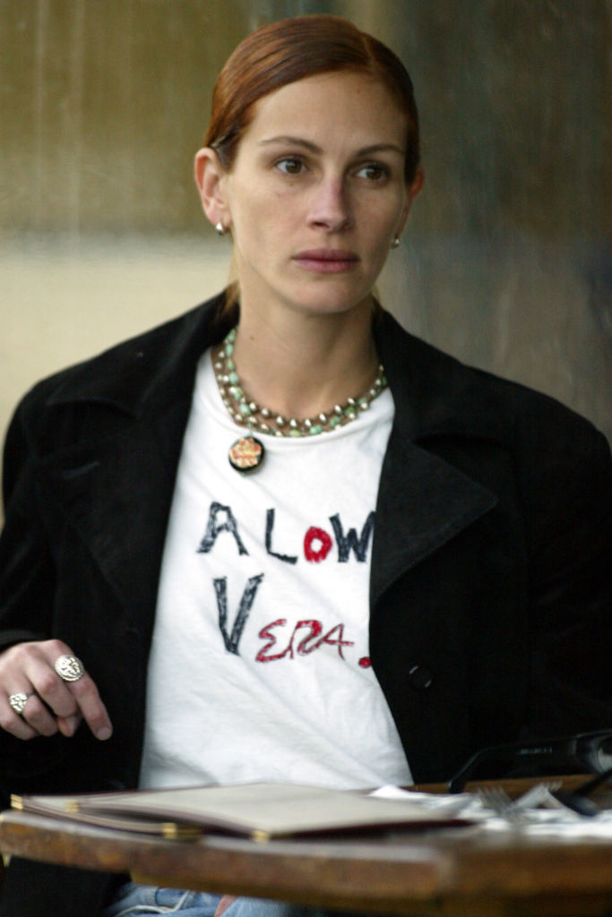 Julia Roberts in casual attire, wearing a T-shirt with "A LOW VERA" written on it, layered necklaces, and a black jacket