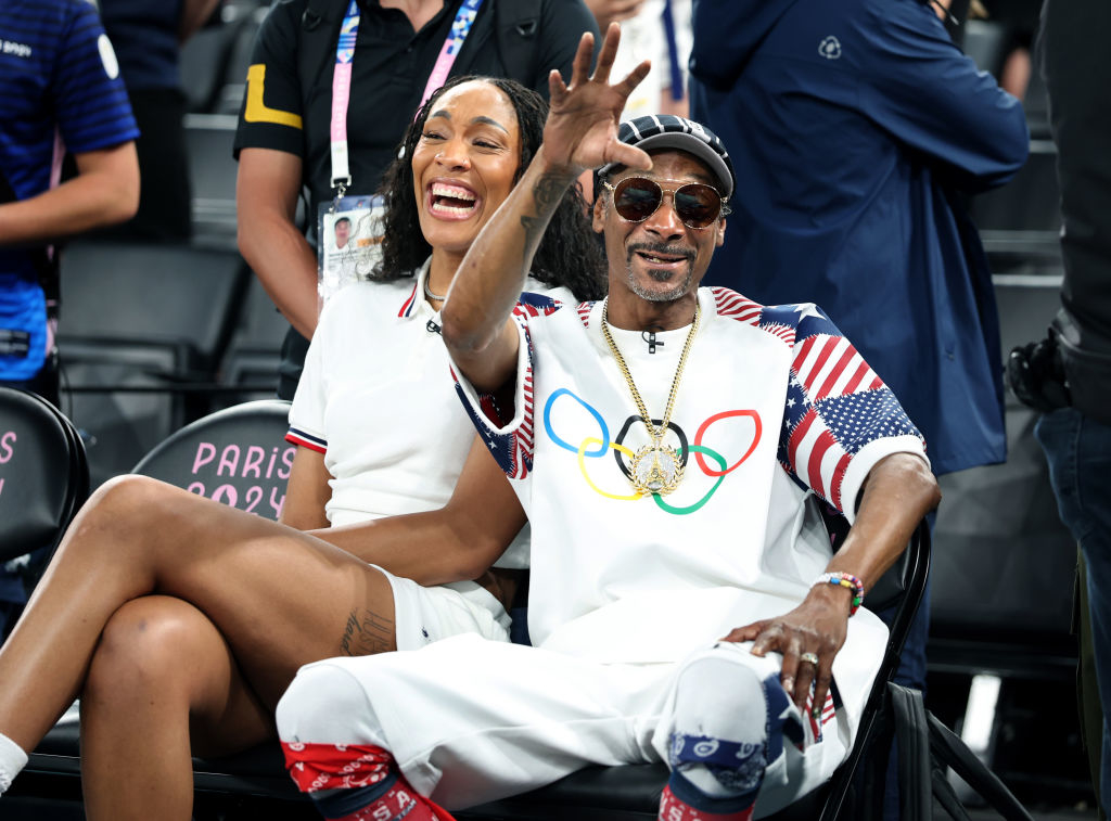 Snoop Dogg and A'ja Wilson sit courtside watching a USA men's basketball game at the Olympics.