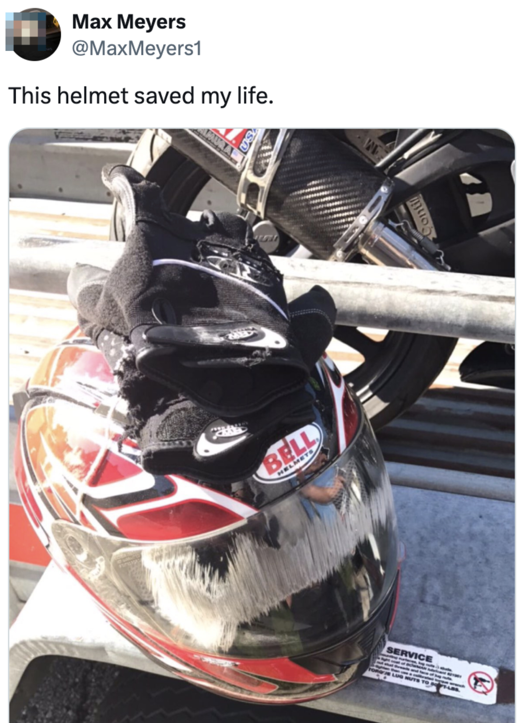 Max Meyers' tweet with a photo of a Bell motorcycle helmet with gloves on top, placed on a metal surface. Text reads: "This helmet saved my life."