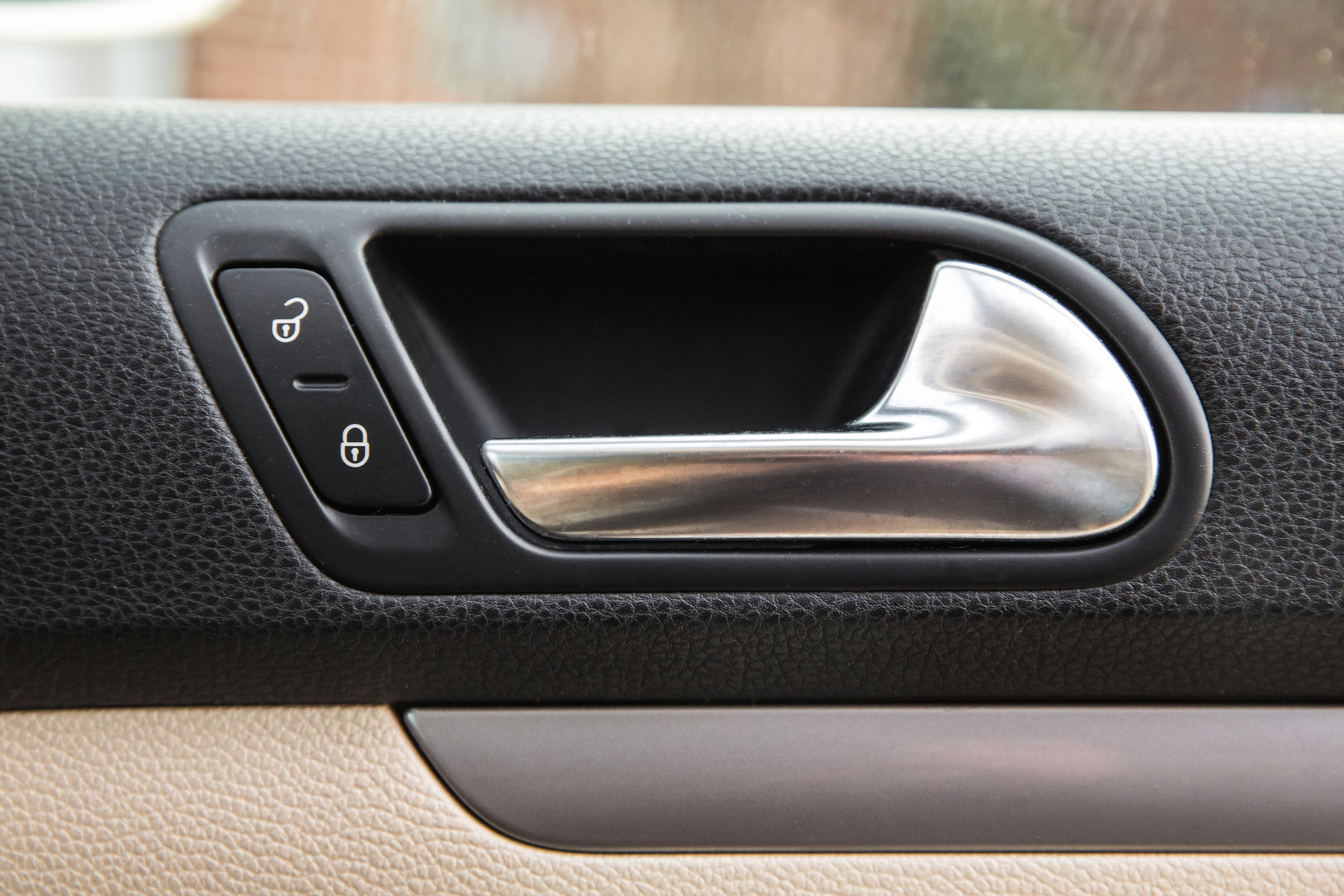 Close-up view of a car interior door handle with lock/unlock buttons