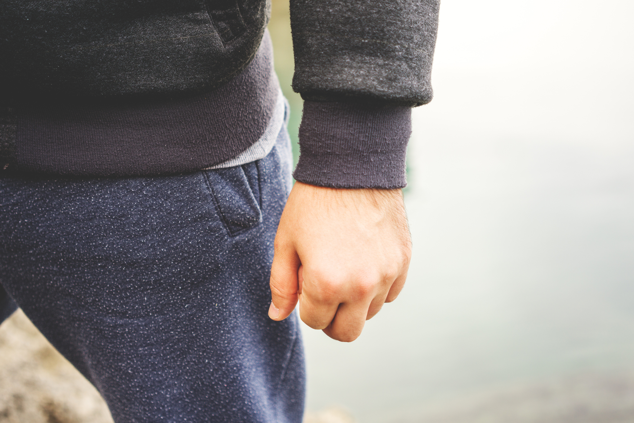 A close-up of a person&#x27;s hand and part of their arm, dressed in a casual sweatshirt and sweatpants