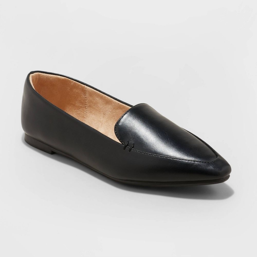 A single black leather loafer with a pointed toe and slight heel on a plain background