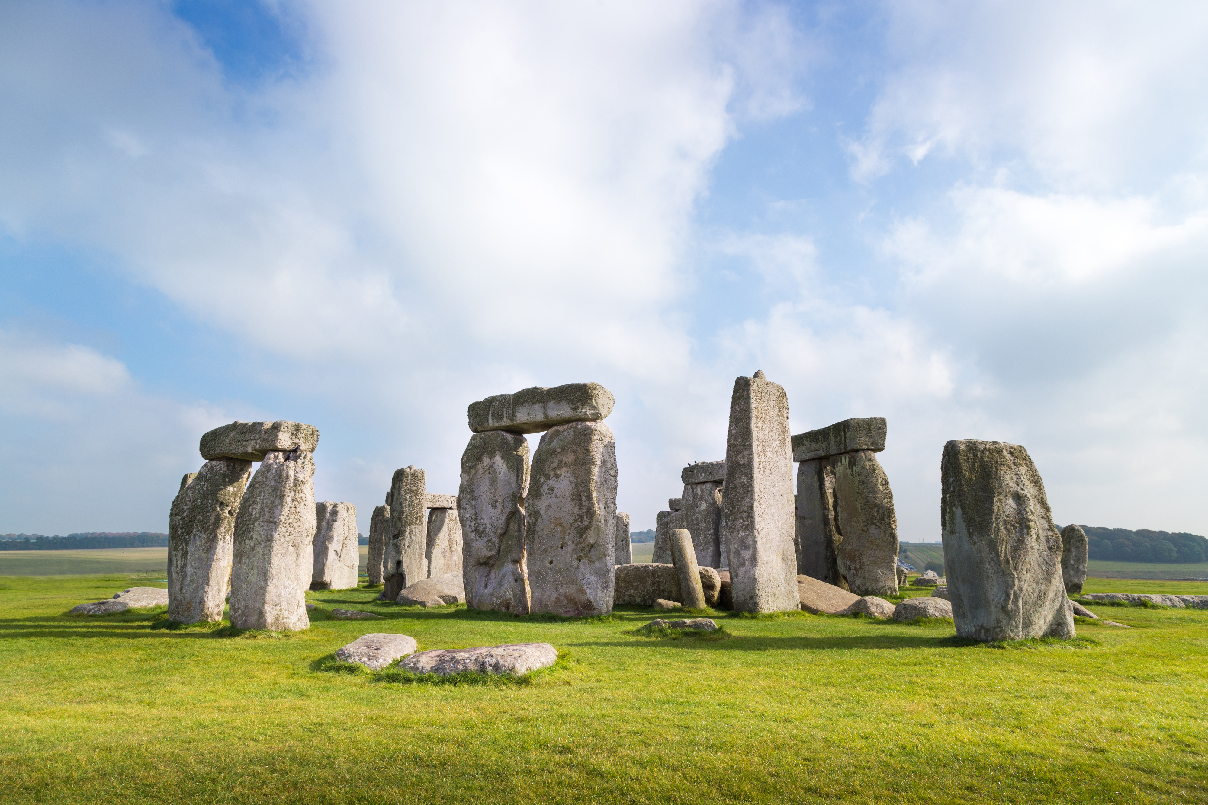 Stonehenge, an ancient stone circle monument in England, with large upright stones arranged in a circular formation on a grassy field under a cloudy sky