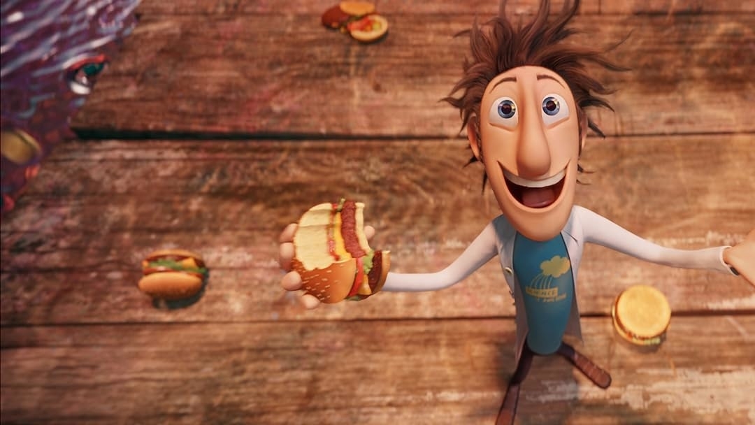 Flint Lockwood from "Cloudy with a Chance of Meatballs" excitedly holds a cheeseburger while more food items fall from the sky around him