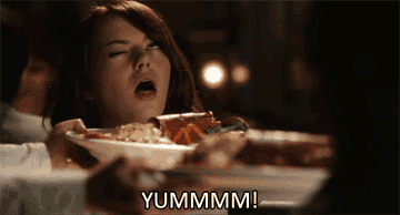 Emma Stone closing her eyes and looking delighted as she is served a plate of food. Text overlay reads "YUMMMM!"