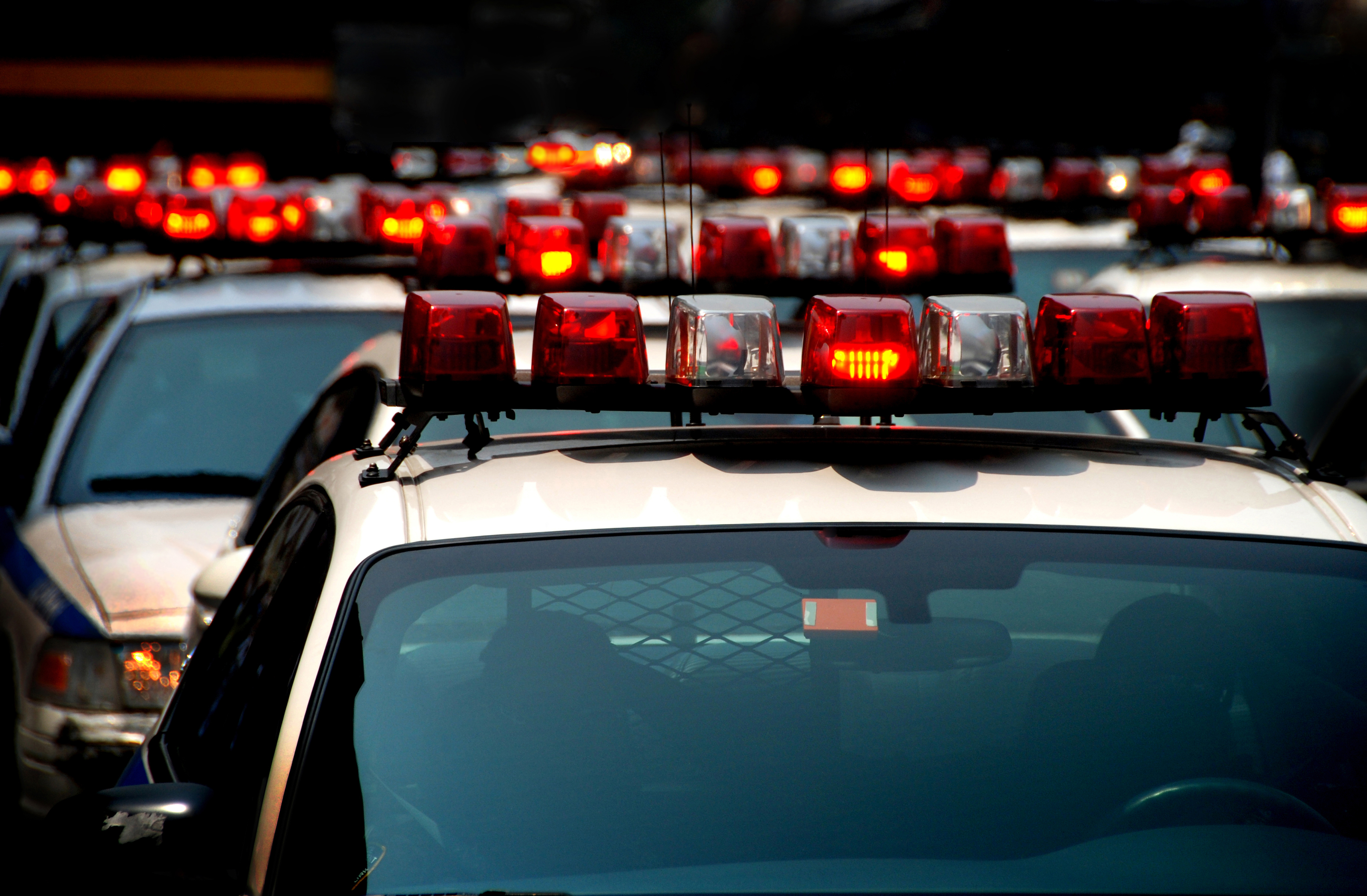 Several police cars with flashing lights are lined up, filling the frame. The image captures the intense and urgent atmosphere of an active situation