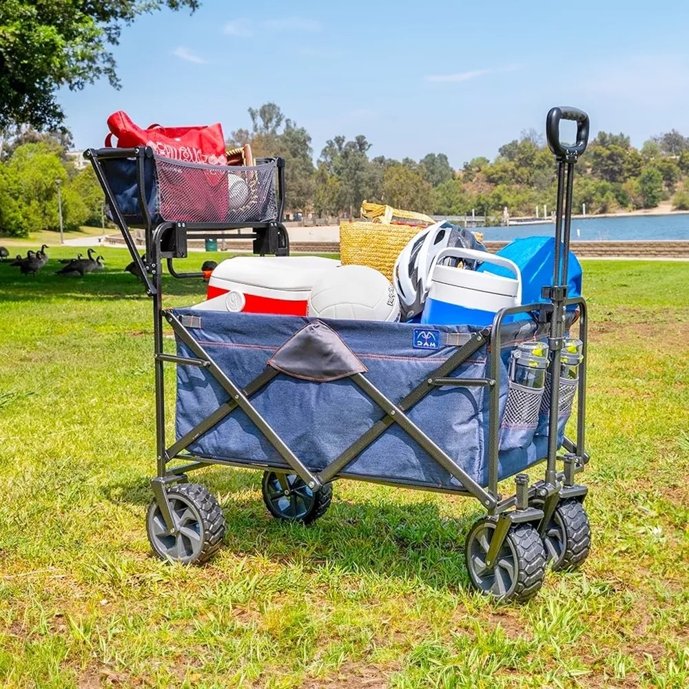 The utility wagon, packed full of outdoor accessories, is on a grassy surface near water