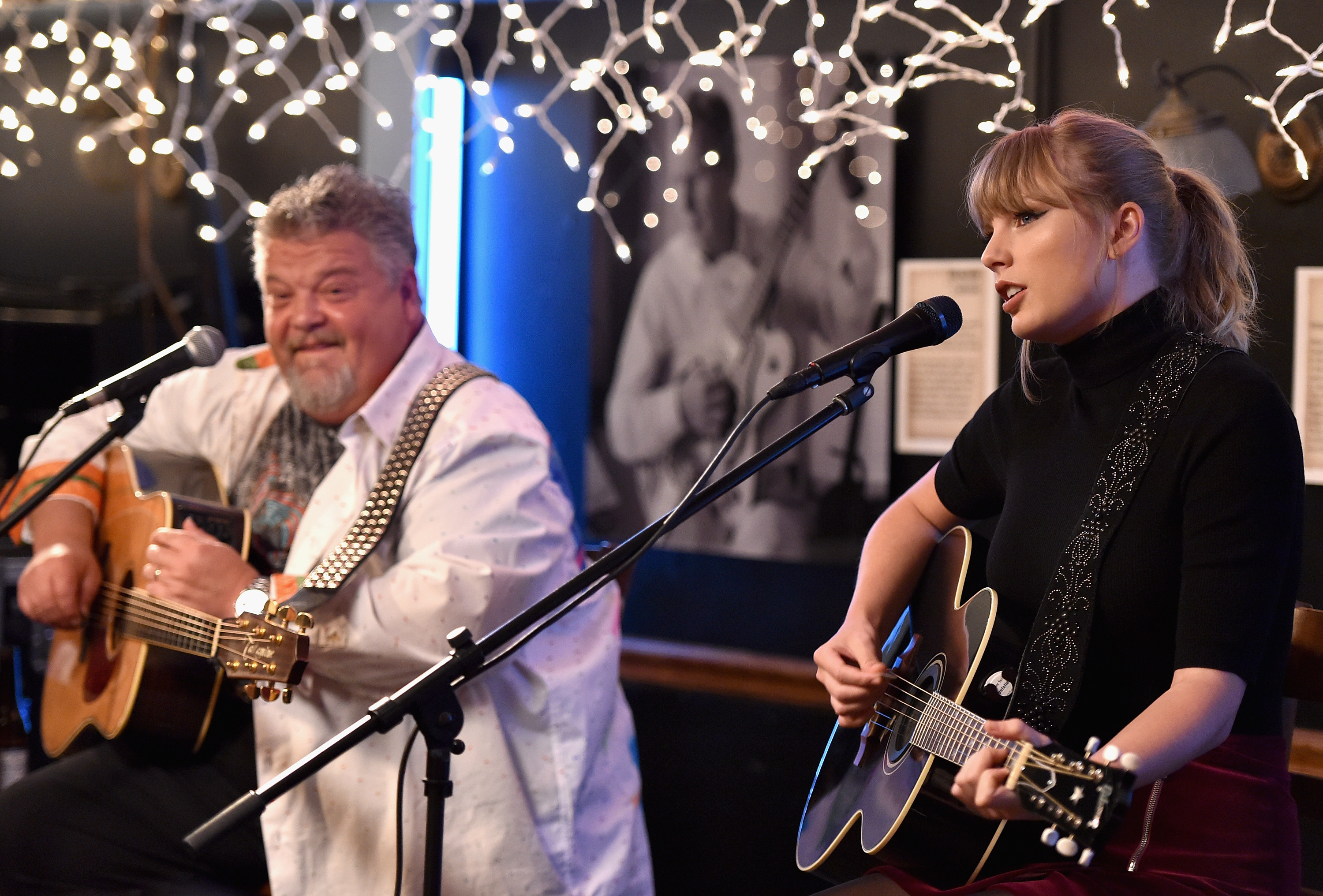 Taylor Swift and Craig Wiseman perform together with guitars under string lights on stage