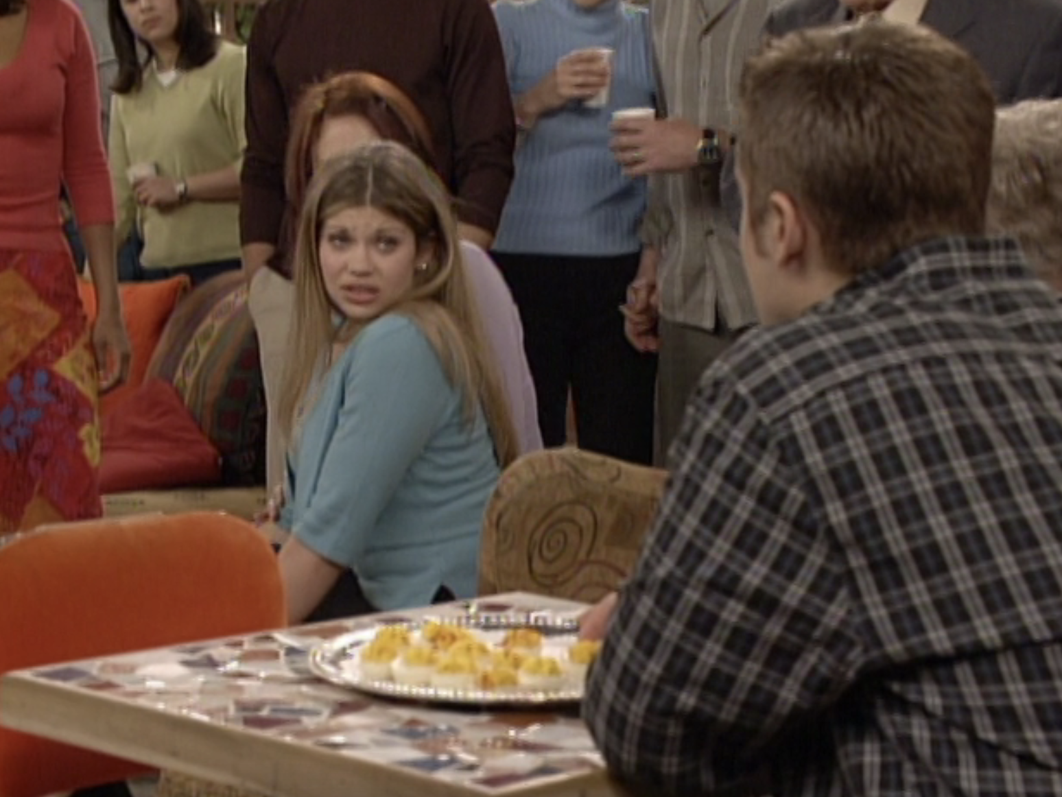 Topanga sitting in a living room, looking back at Cory, surrounded by other friends and family from &quot;Boy Meets World.&quot;