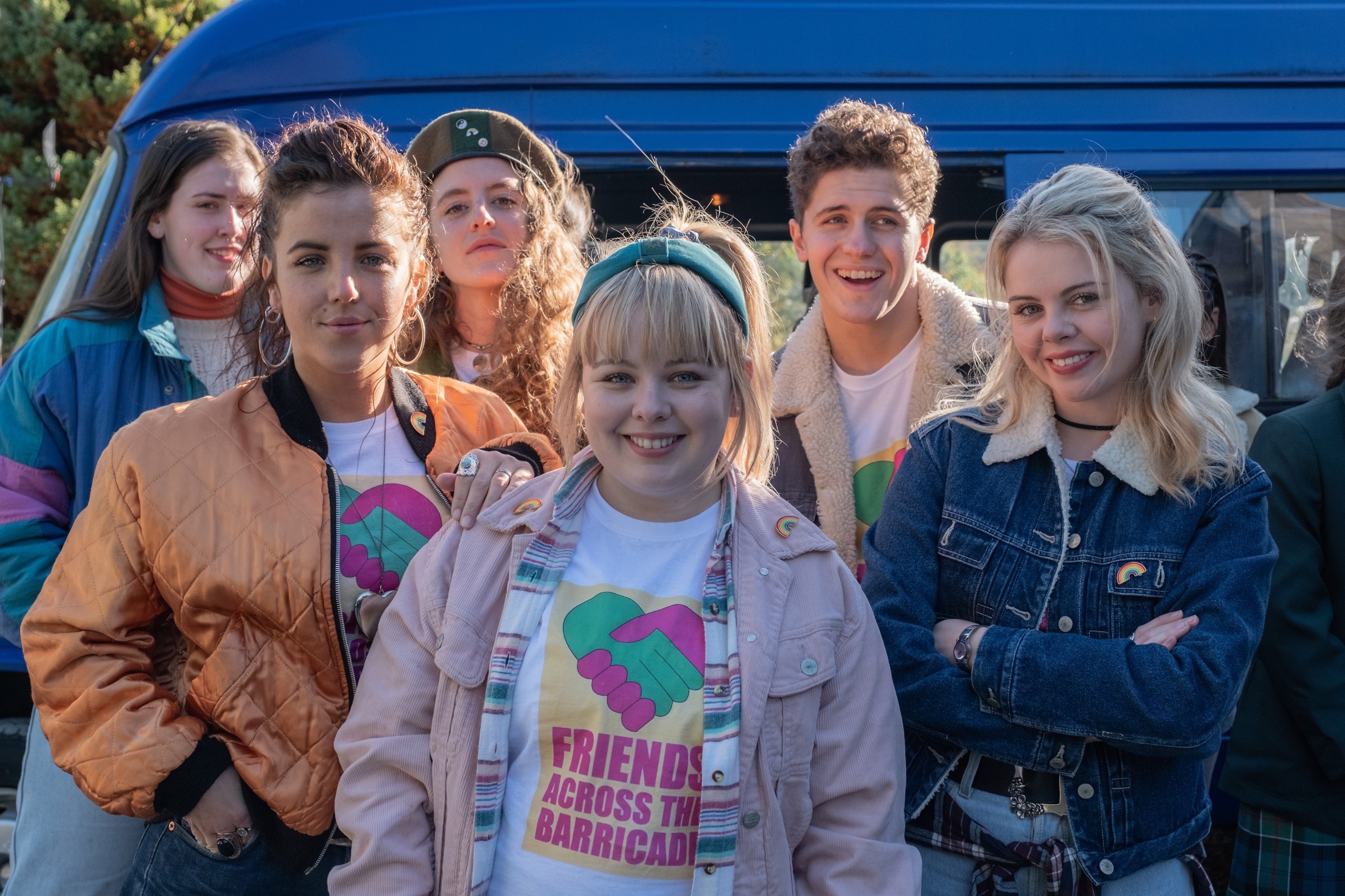 Saoirse-Monica Jackson, Louisa Harland, Nicola Coughlan, Jamie-Lee O'Donnell, Dylan Llewellyn, and Siobhán McSweeney pose in casual 1990s-style outfits in front of a van