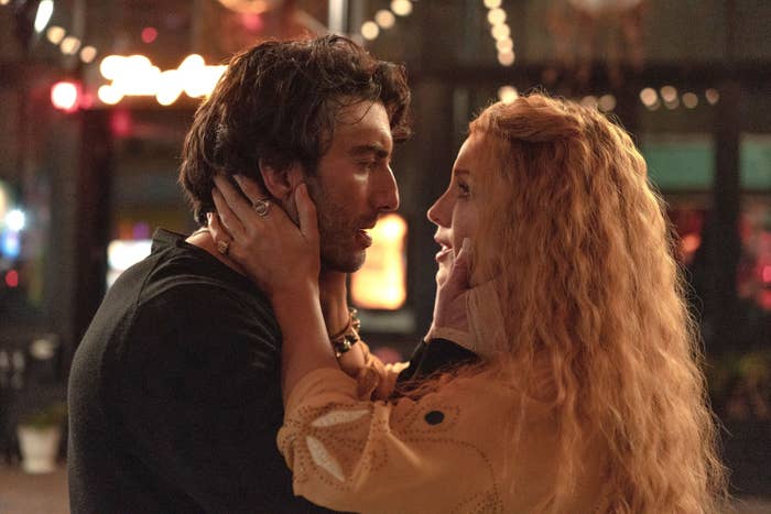 Justin Baldoni and Blake Lively in an emotional scene, looking at each other and holding each other's faces, in a dimly lit setting