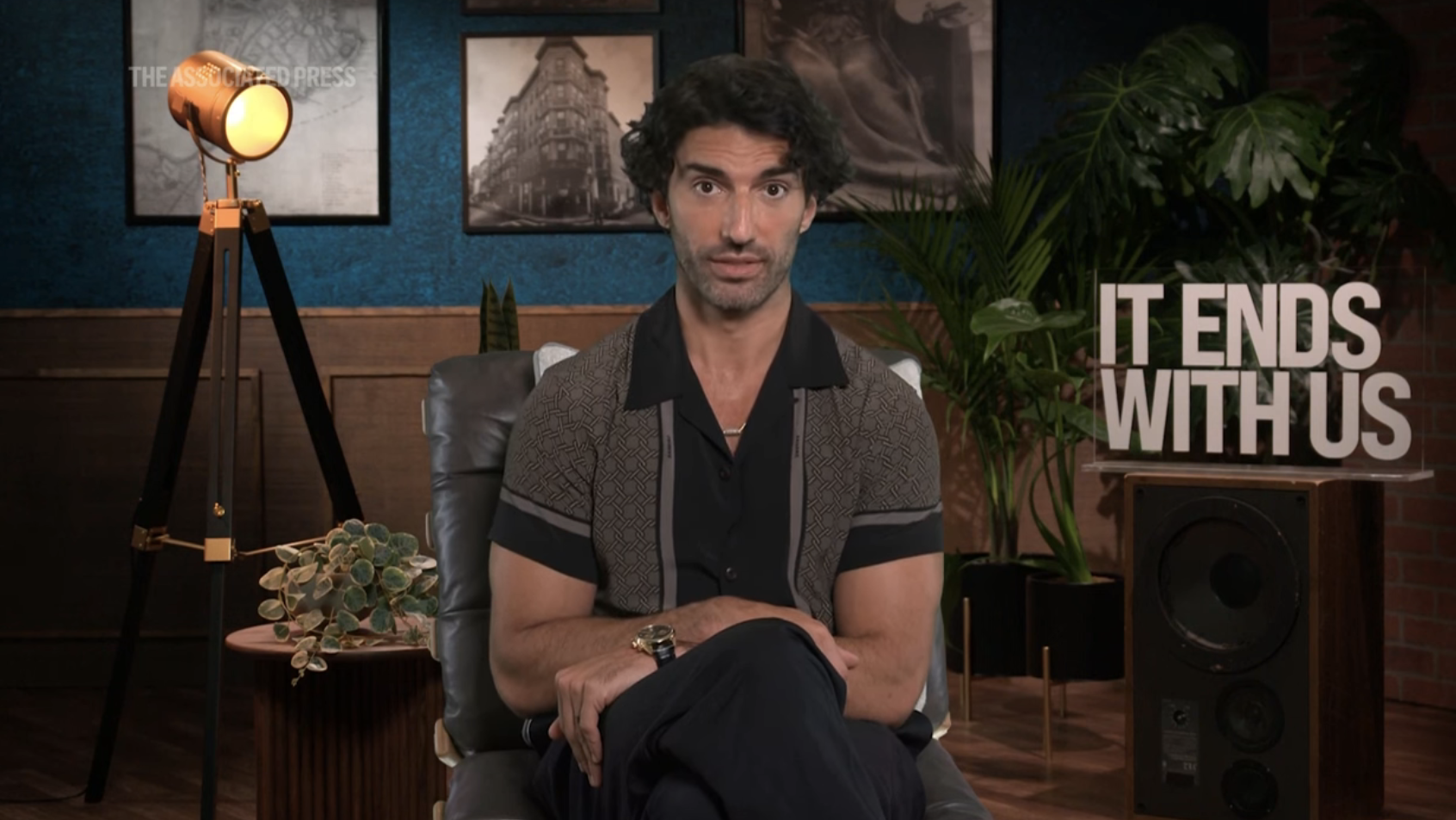 Justin Baldoni sitting in a chair, discussing the title "It Ends With Us," with studio decor in the background