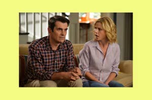 Ty Burrell and Julie Bowen sit on a couch, both wearing casual clothes, in a scene from the TV show Modern Family