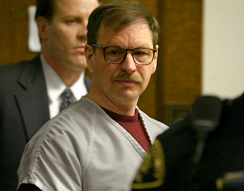 Two men, including Gary Ridgway in prison attire, stand in what appears to be a courtroom