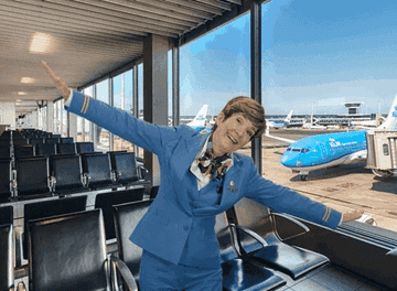 Gif of fight attendant spreading arms in excitement in an empty airport lounge
