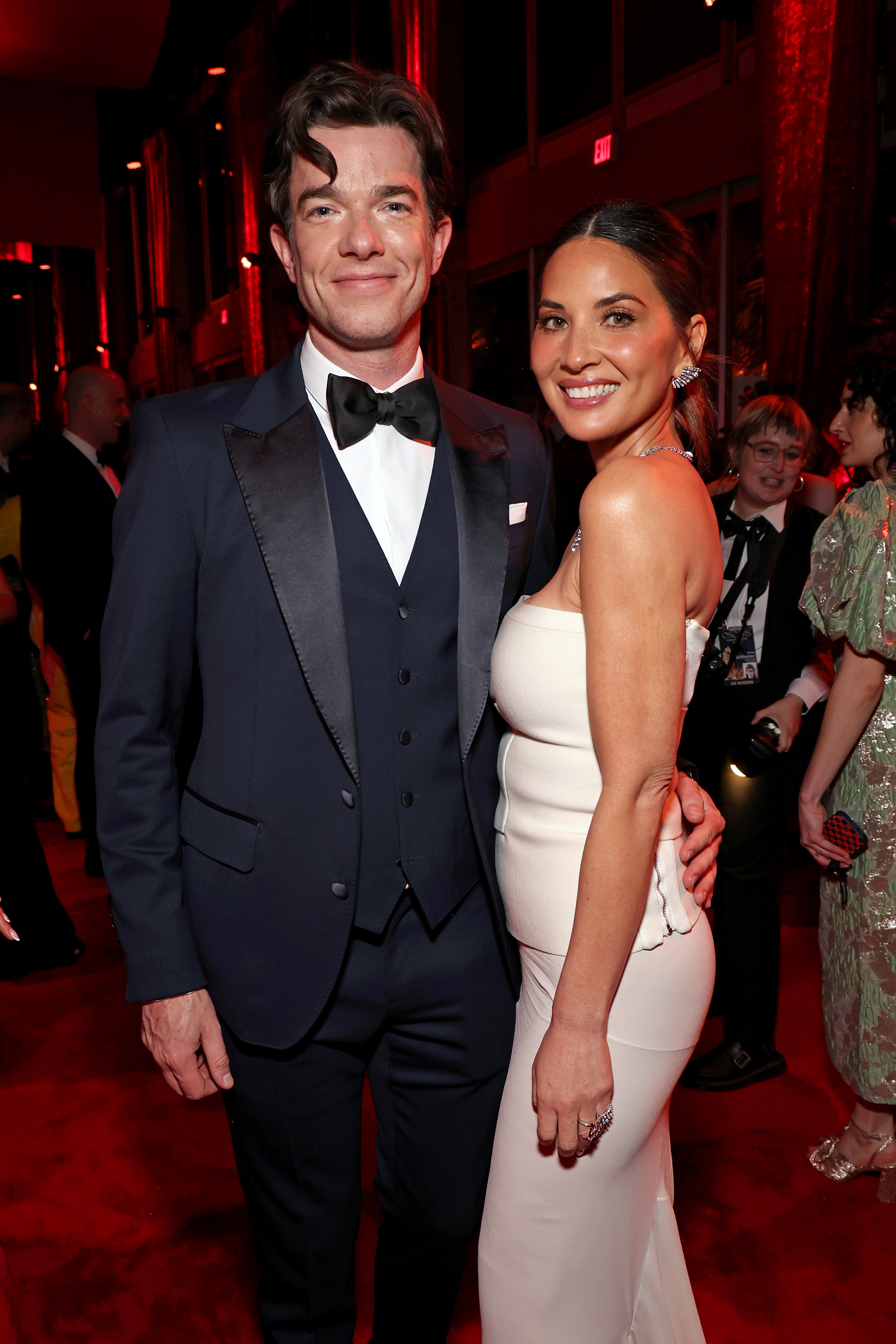 John Mulaney in a tuxedo and Olivia Munn in an elegant strapless dress pose together at a red carpet event