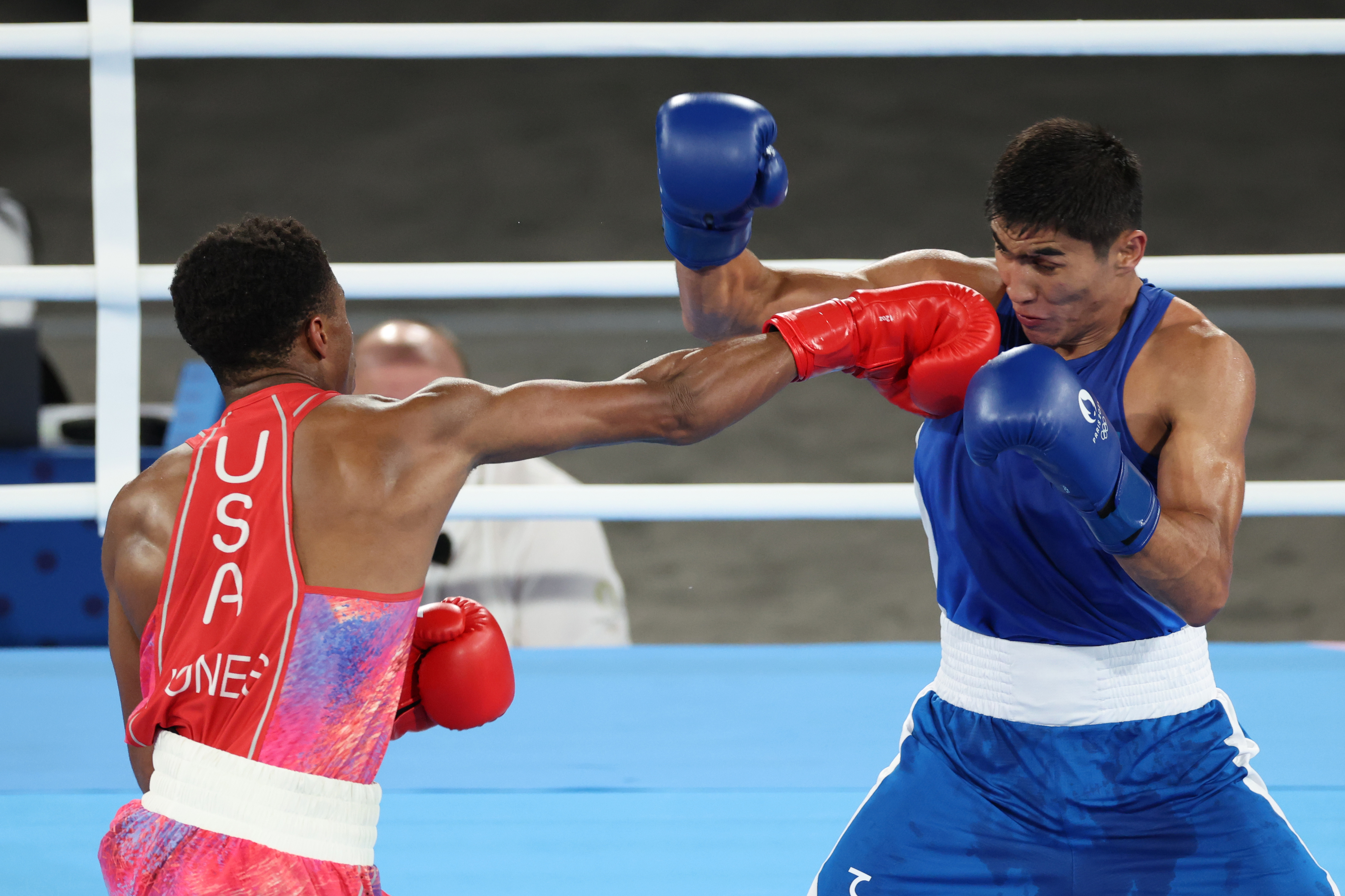Two boxers in action in a boxing ring. The boxer on the left has "USA" on their back, and the one on the right is wearing blue