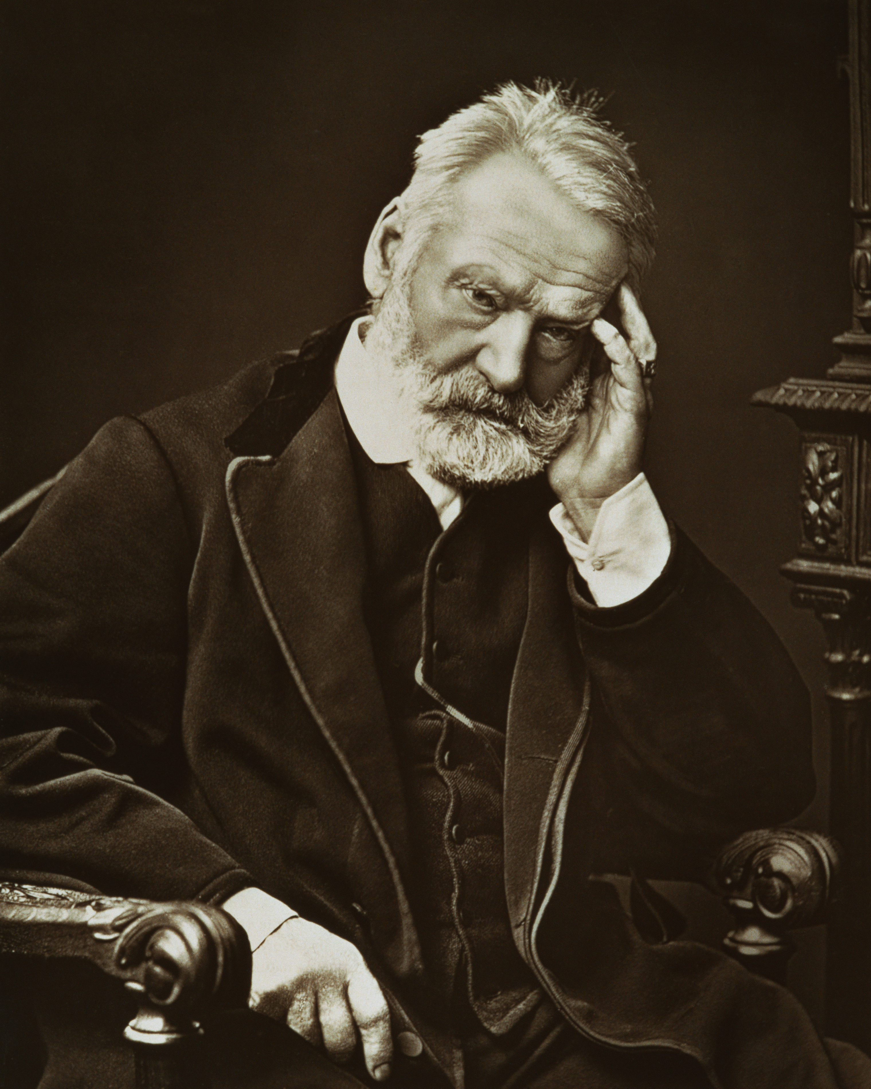 Victor Hugo seated with his head resting on his hand, wearing a dark, formal coat and vest