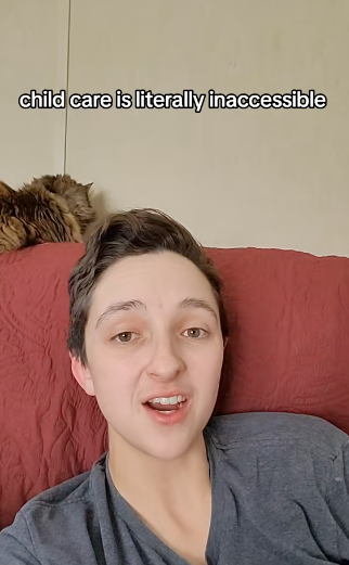 Person with short hair and gray shirt speaking on a red couch, with text above saying "child care is literally inaccessible." A cat is resting on top of the couch