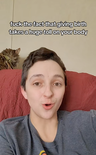 Person with short hair speaking with a surprised expression, a cat in the background. Text reads: "fuck the fact that giving birth takes a huge toll on your body."