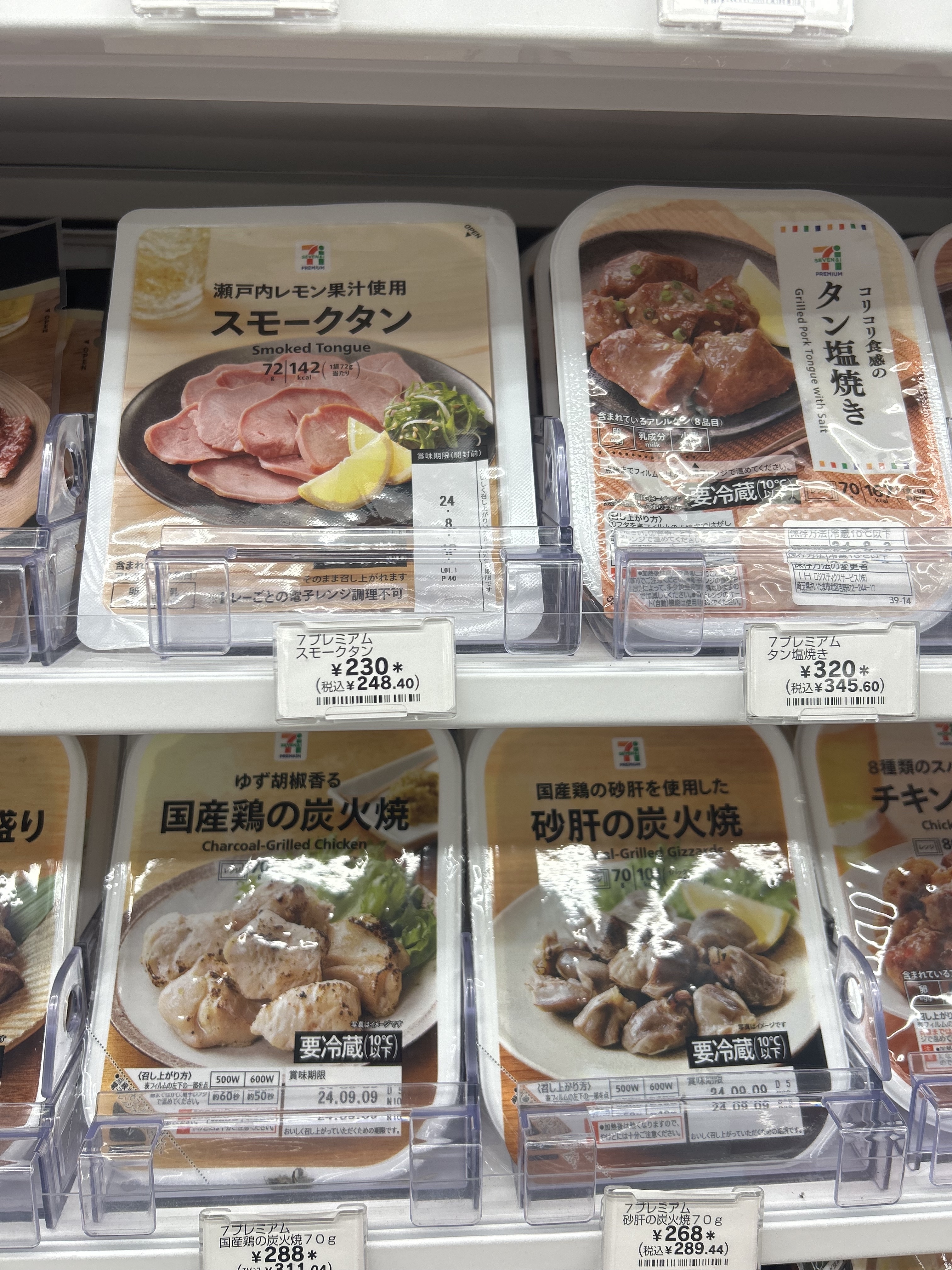 Packages of ready-to-eat meals, including smoked tongue, char-grilled beef, and chicken karaage, displayed on store shelves with pricing labels