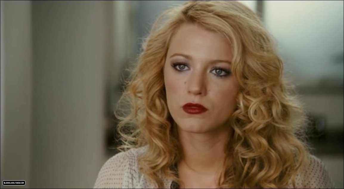 No sé quién está en la imagen. Mujer con cabello rizado largo y maquillaje prominente. Está seriamente mirando al frente