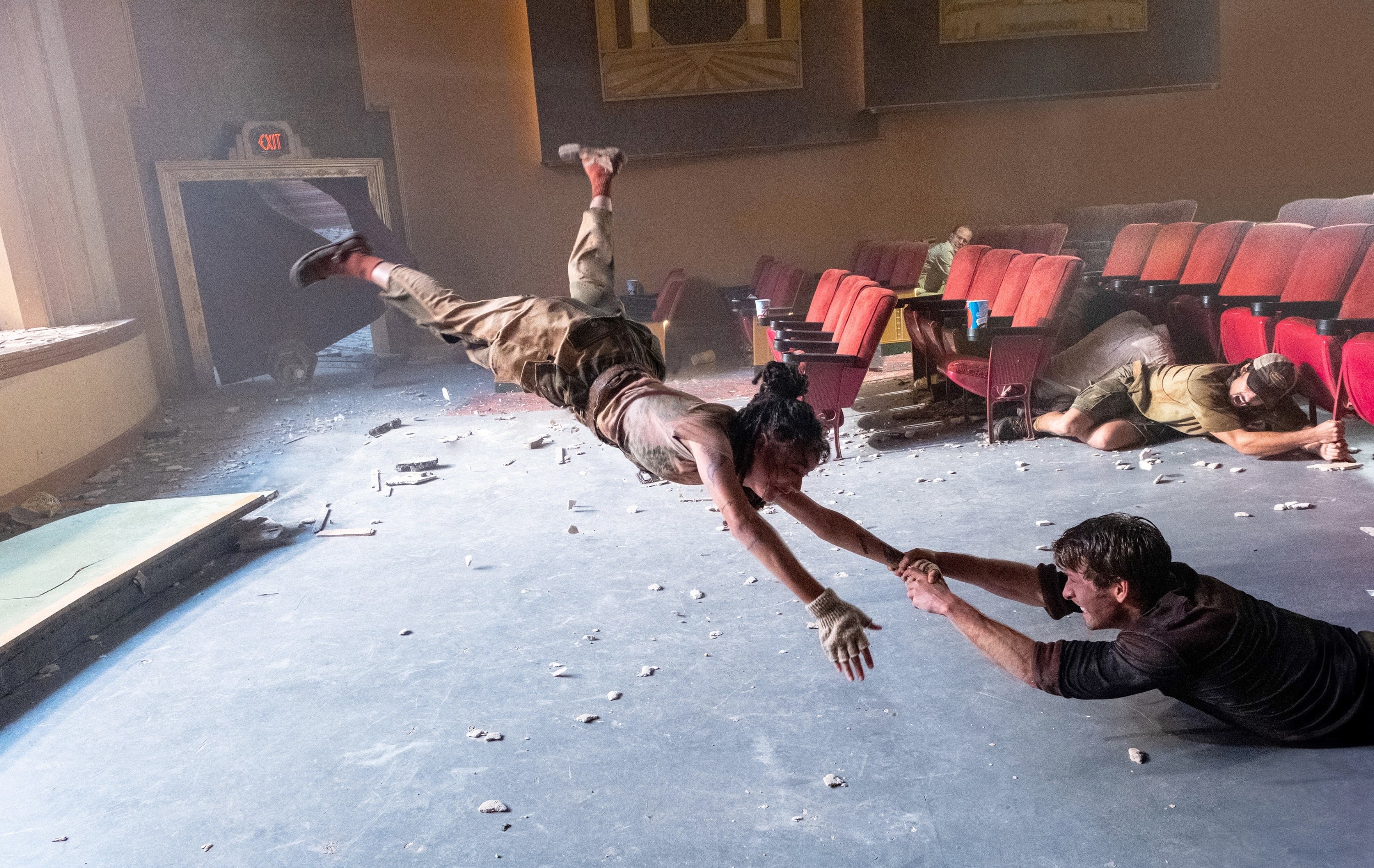 Sasha Lane flying in the air and Glen Powell holding her hand from the floor in &quot;Twisters&quot;