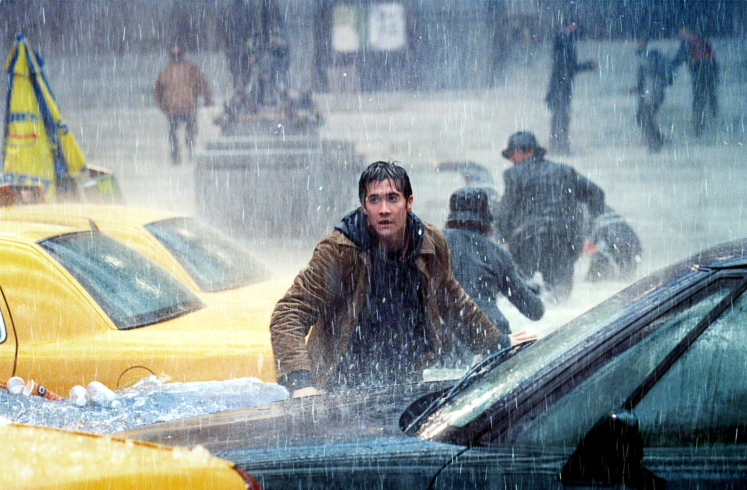 Jake Gyllenhaal runs through a flooded street with cars and people in the background in &quot;The Day After Tomorrow&quot;