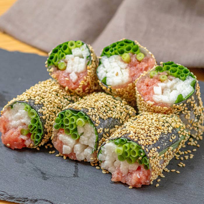 6つのごまとのりで包まれた生春巻きが石のプレートにのっています。