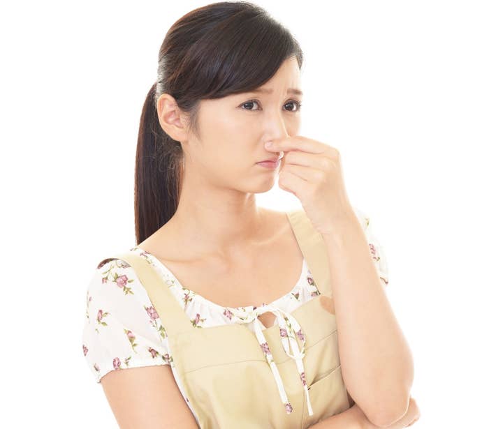 女性が鼻をつまんでいるイメージ写真