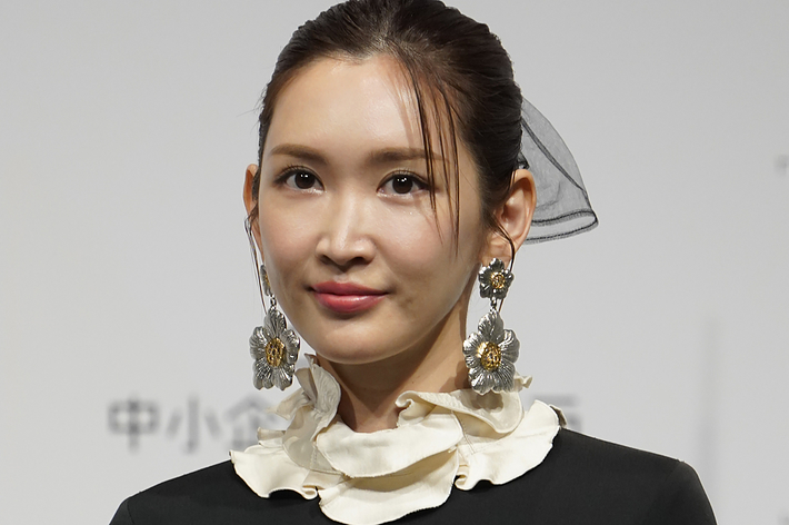 女性が黒いクラシックなドレスと大きなイヤリングを身に着けている。