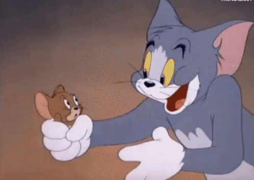 Tom, a grey cat, holds Jerry, a small brown mouse, in his hand. Both characters show a mix of surprise and curiosity. They are from the cartoon "Tom and Jerry."