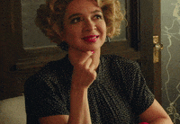 Maya Rudolph from "The Happytime Murders" is sitting with her chin resting on her hand, smiling and looking upward.
