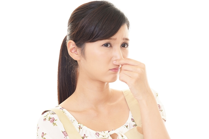 女性が鼻をつまんでいるイメージ写真