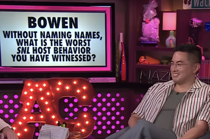 Andy Cohen and Bowen Yang are on a TV set for "TRUTH or KINK!" discussing the worst SNL host behavior seen, with lit decor and a question displayed on screen