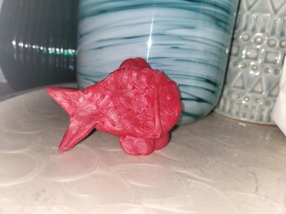 Red fish-shaped sculpture on a table in front of patterned vases
